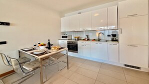 A modern kitchen with white cabinets, a dining table with chairs, and a built-in oven.