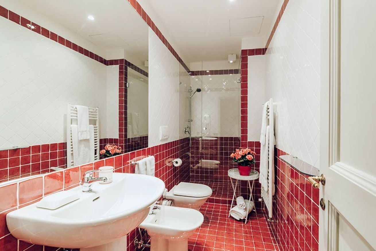 Une salle de bain avec un grand lavabo, deux toilettes, une douche et un miroir.