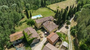 An aerial view of a rural property with multiple buildings, a swimming pool, and surrounding greenery.