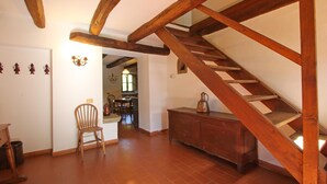 A wooden staircase with a rustic design, a wooden chair, and a cabinet in a room with tiled flooring and white walls.