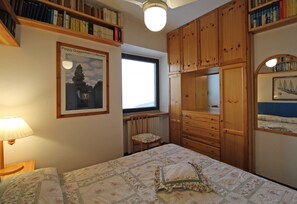 Una camera da letto con un letto, armadietti in legno, una libreria e un quadro appeso al muro.