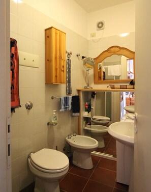 Un bagno con due servizi igienici, un lavandino, uno specchio e un portaservizi.