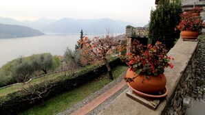 A stone building with a view of a lake and mountains. - Two-room apartment in Residence with swimming pool and panoramic lake view in Sale Marasino (Sale Marasino)