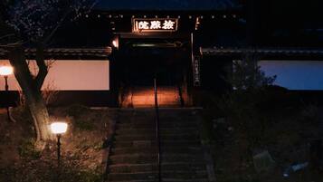 Un edificio japonés tradicional con una entrada de madera y un sendero de piedra que conduce a él.