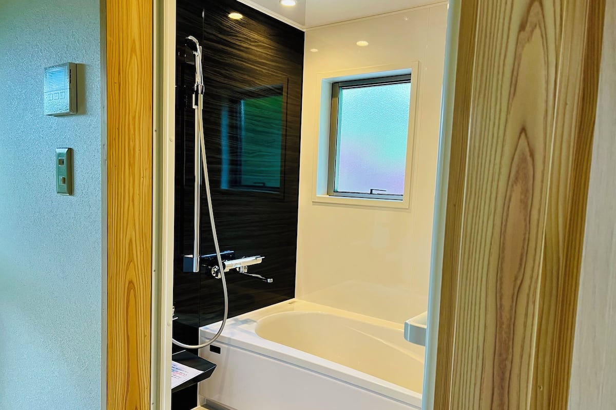 A modern bathroom with a bathtub, a shower, and a window.