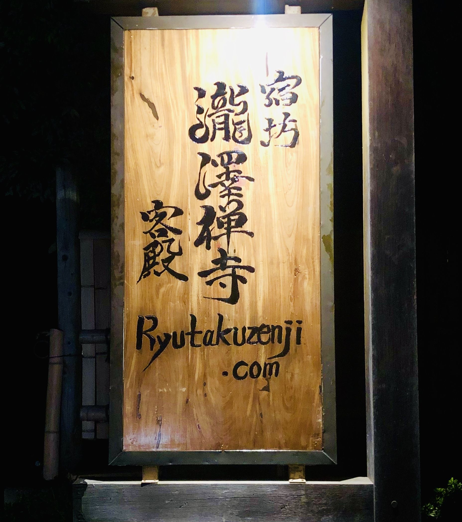 Een houten bord met Japanse karakters en de website Ryutakuzeni.com.