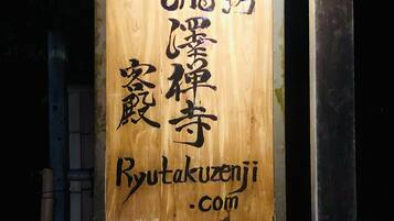Een houten bord met Japanse karakters en de website Ryutakuzeni.com.