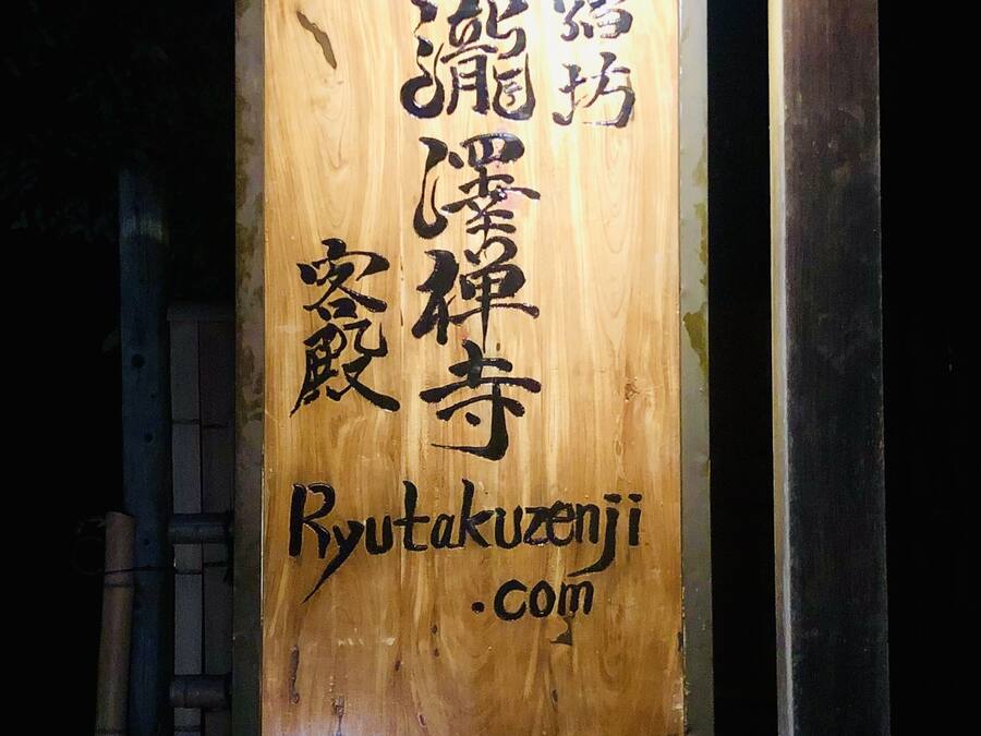 Een houten bord met Japanse karakters en de website Ryutakuzeni.com.