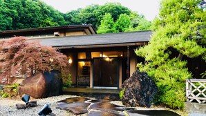 A traditional Japanese house with a tiled roof, surrounded by a garden with rocks, a pond, and various plants. - Ryutakuzenji (Takasaki)
