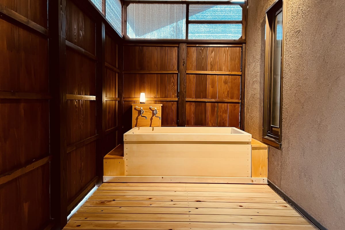 A wooden interior with a large bathtub, wooden walls, and a window.