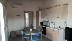 A compact kitchen with a dining table, blue chairs, a microwave, a toaster, and a TV. - Sea view Penthouse sea view (Quartu Sant'Elena)