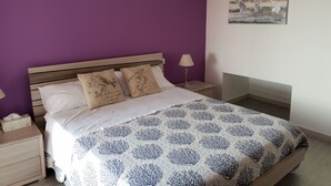 A bedroom with a bed, a nightstand, a lamp, and a wall art piece. - Sea view Penthouse sea view (Quartu Sant'Elena)