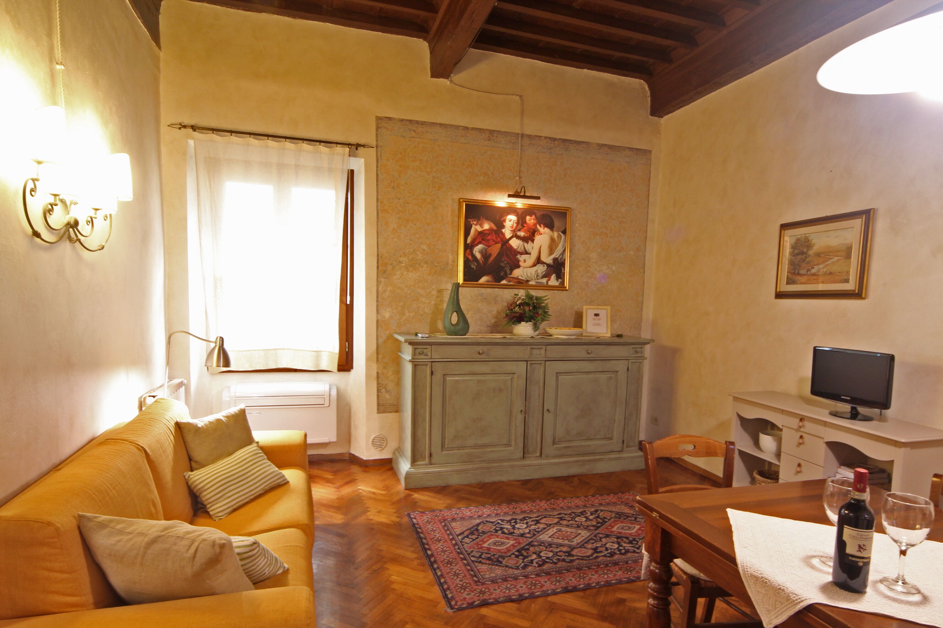 Un salon confortable avec un canapé, une table à manger et des chaises, un téléviseur et un tableau accroché au mur.