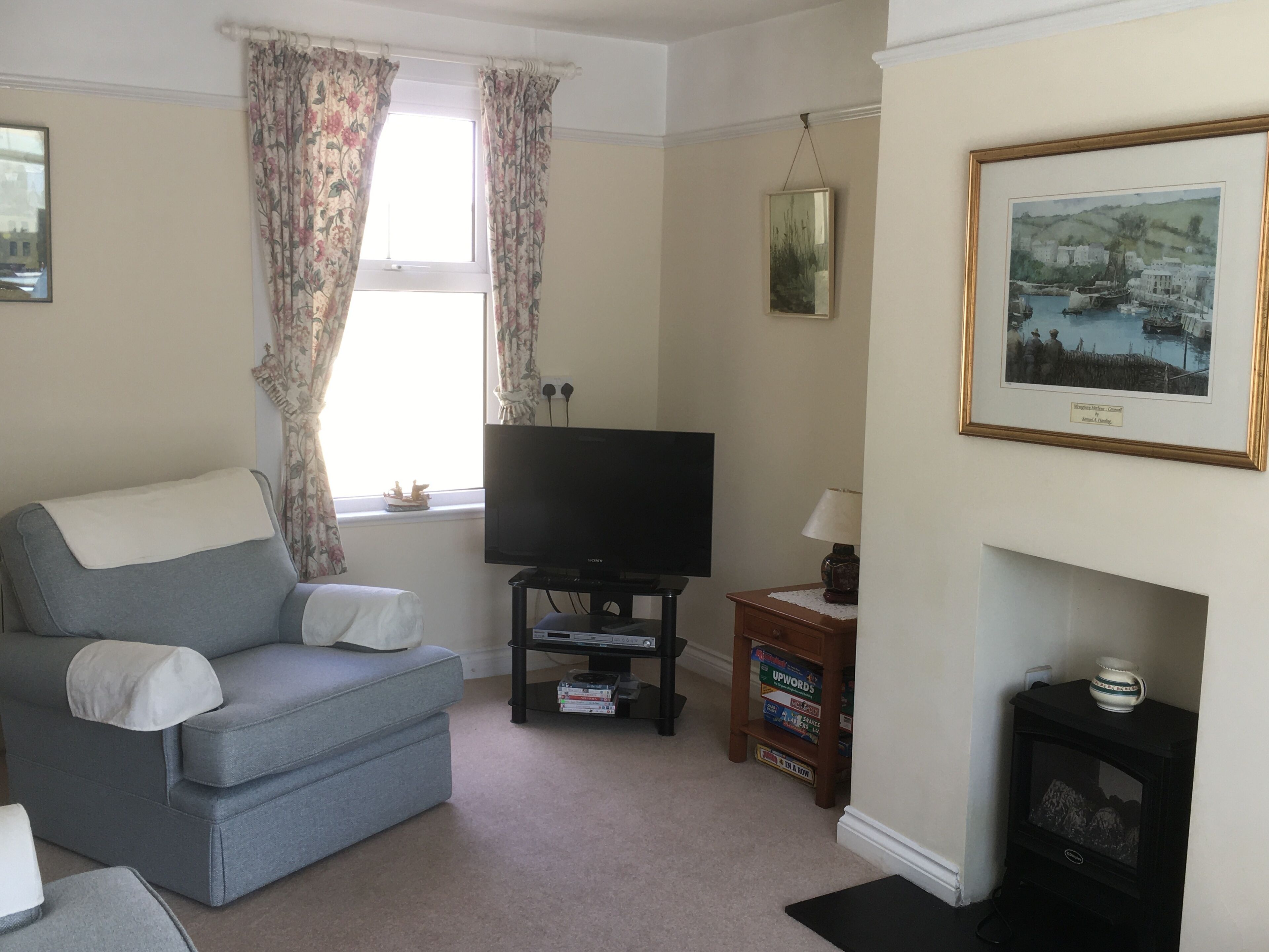 A living room with a sofa, a television, a fireplace, and a framed picture on the wall.
