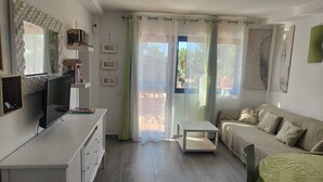 A living room with a sofa, a TV, a small table, and a chair. - Apartment/ flat - Corralejo (Corralejo)