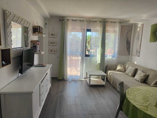 A living room with a sofa, a TV, a small table, and a chair.