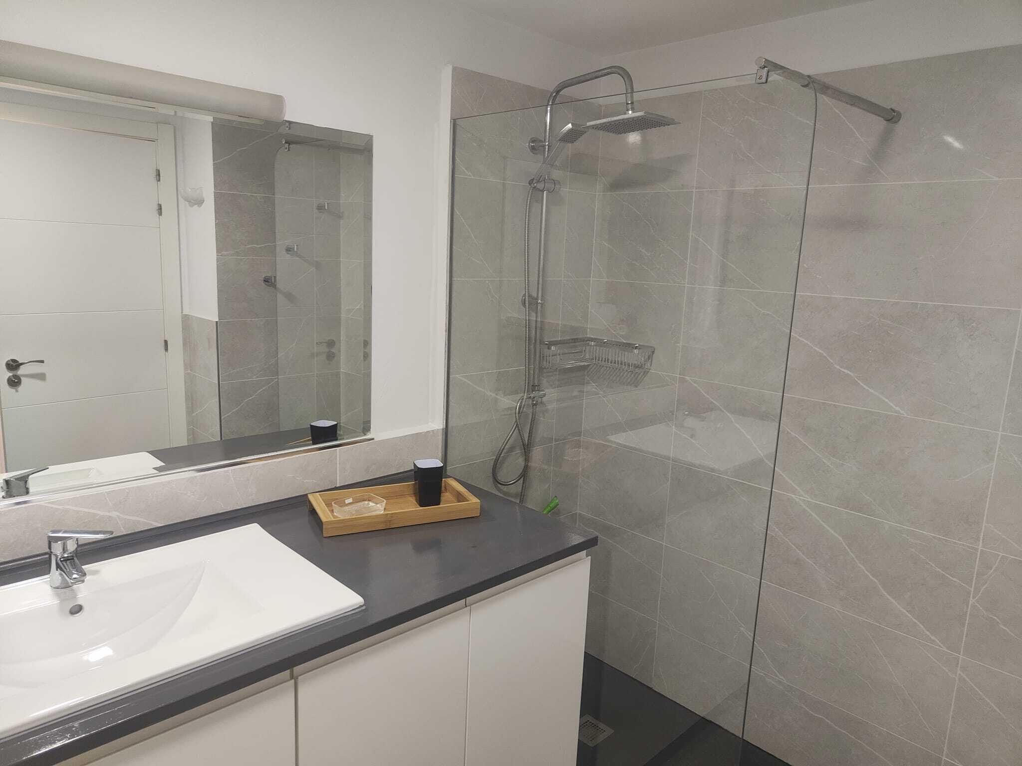 Ein Badezimmer mit Duschkabine aus Glas, Waschbecken und Spiegel.