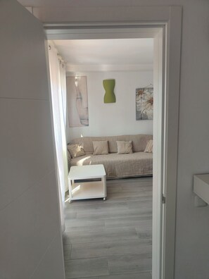 An interior view of a room with a sofa, a white side table, and a painting on the wall. - Apartment/ flat - Corralejo (Corralejo)