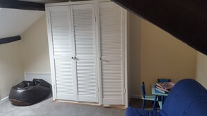 A room with a white closet, a bean bag chair, a small table with books, and a blue chair. - Family House with garden in Lake District National Park - sleeps 8 (Bootle)