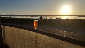 A glass of beer on a ledge overlooking a body of water with boats and a sunset in the background. - Family House with garden in Lake District National Park - sleeps 8 (Bootle)