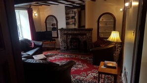 A cozy living room with a fireplace, a sofa, a coffee table, and a lamp. - Family House with garden in Lake District National Park - sleeps 8 (Bootle)