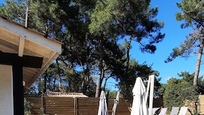 An outdoor patio area with wooden flooring, outdoor furniture, and umbrellas. - House / Villa - Lège-Cap-Ferret (Lège-Cap-Ferret)