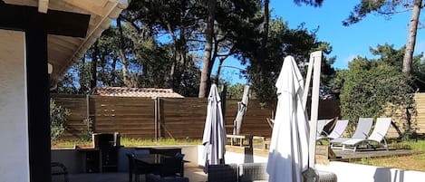 An outdoor patio area with wooden flooring, outdoor furniture, and umbrellas.