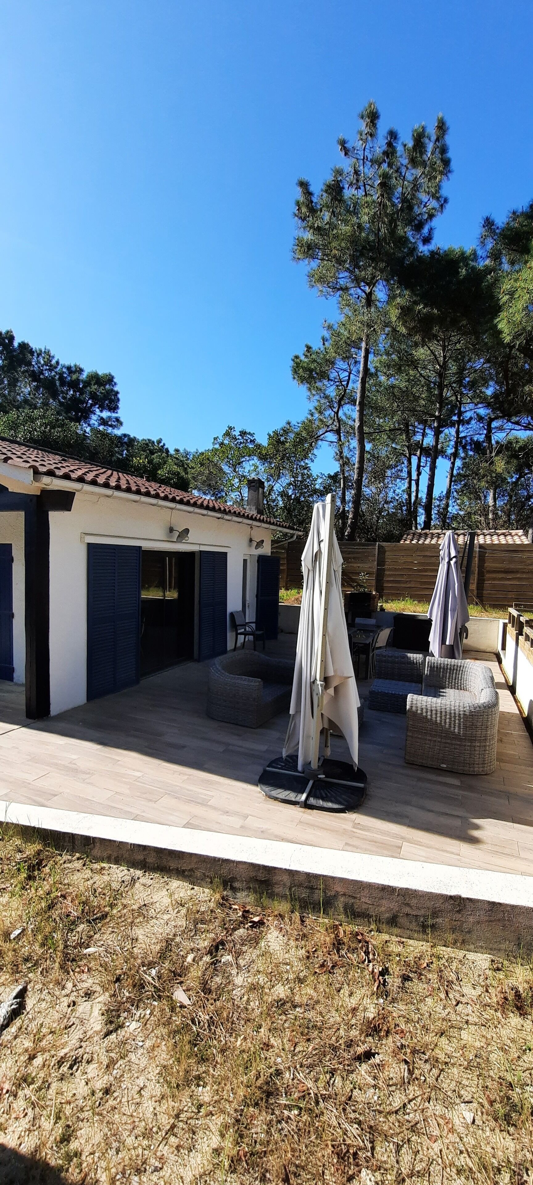 A patio area with outdoor seating, a covered table, and a building with a tiled roof.