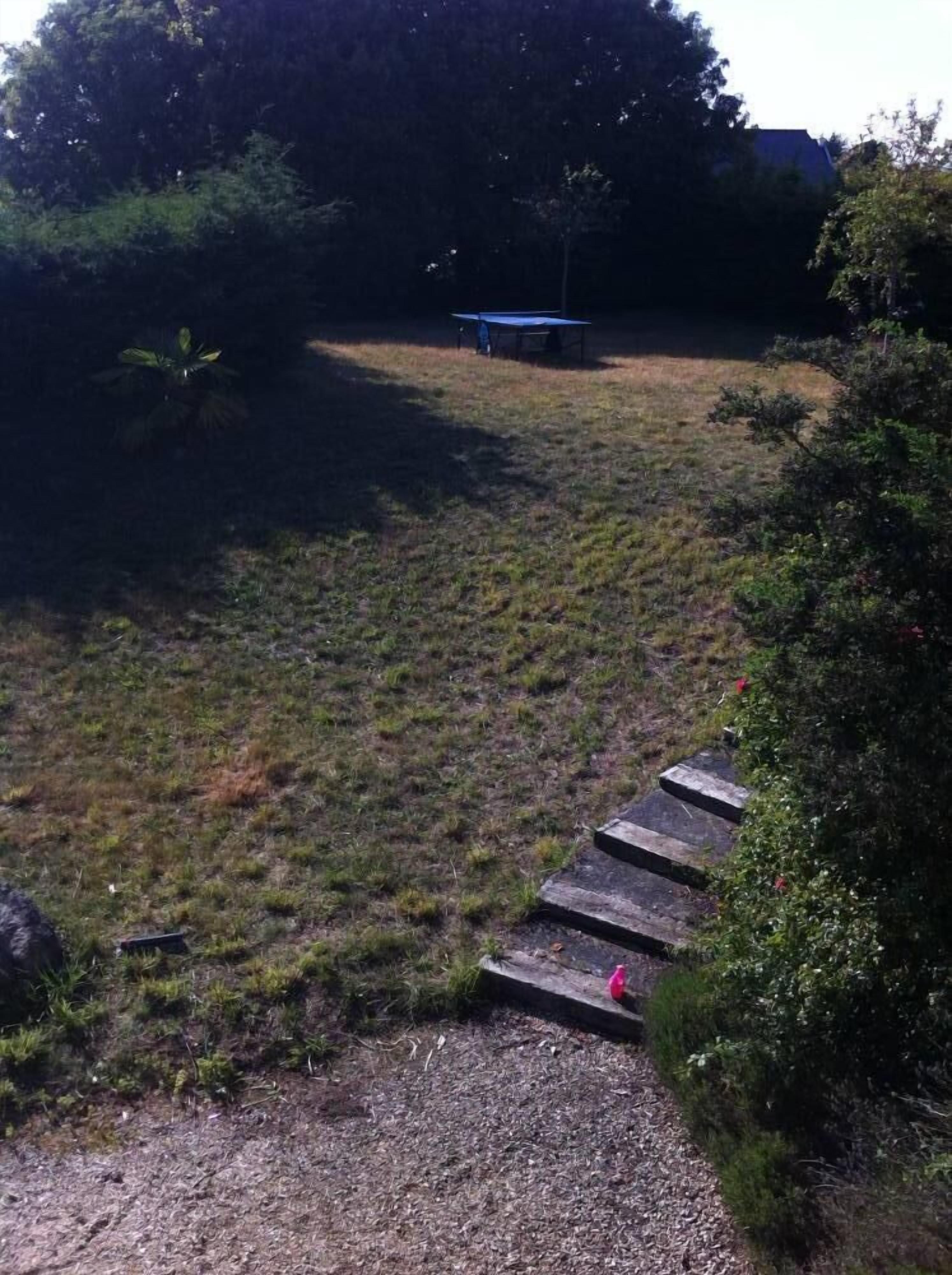 A grassy area with a small wooden structure and steps leading up to it.