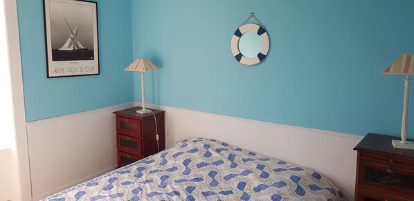 Un dormitorio con cama, cómoda, lámpara, un cuadro en la pared y una decoración de boia.