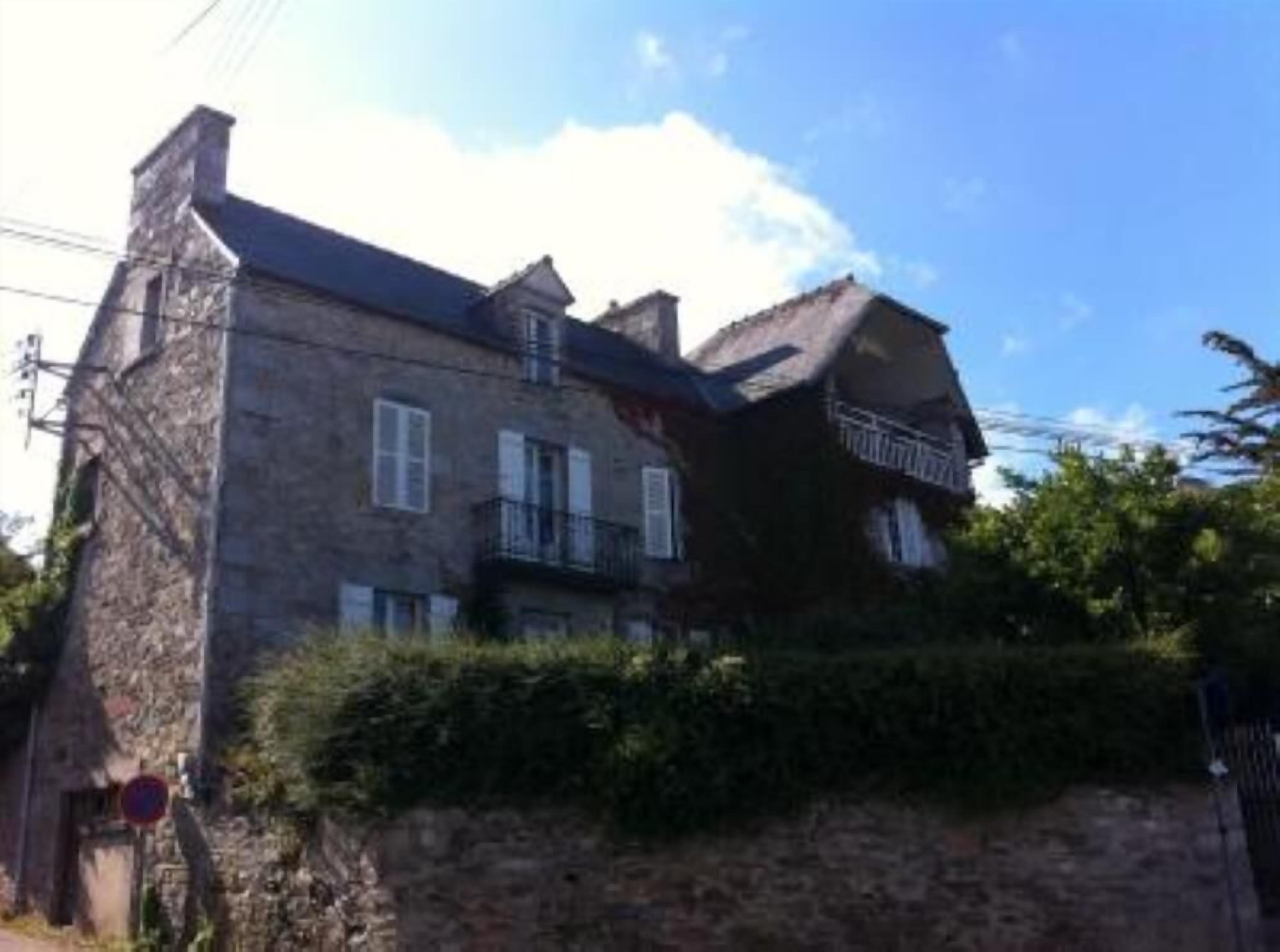 A stone building with a steep roof, multiple windows, and a balcony.