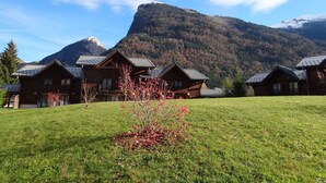 A row of wooden cabins with sloped roofs, set against a backdrop of a mountain and clear sky. -  Homely ground floor 2 bedroom apartment with stunning views  (Samoëns)