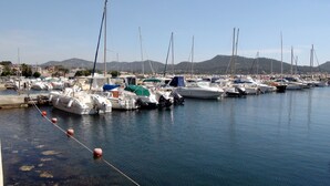A marina with numerous boats docked, calm water, and a mountainous backdrop.