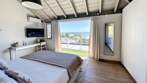 Un dormitorio con cama, escritorio, televisor y ventana grande con vistas al exterior.