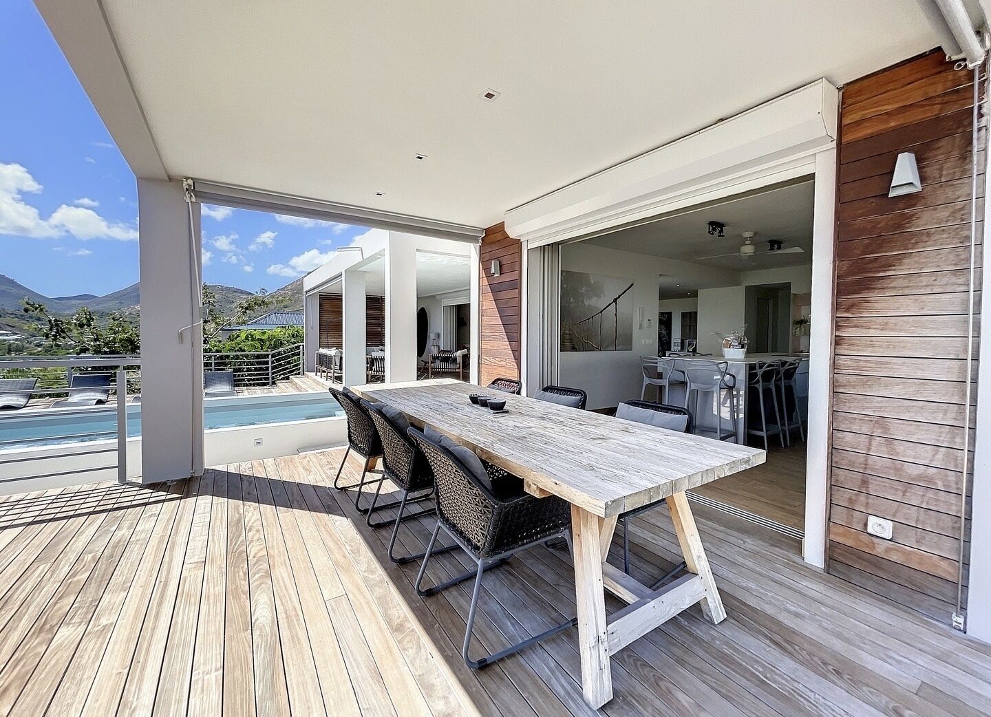 A wooden deck with a pool, outdoor seating, and a view of the mountains.