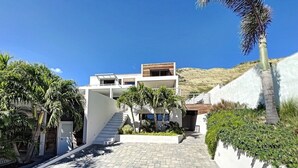 Una casa moderna de dos pisos con un camino de entrada pavimentado que conduce a una escalera.