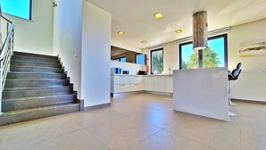 Une cuisine moderne dotée d’un îlot central, d’un escalier et de grandes fenêtres.
