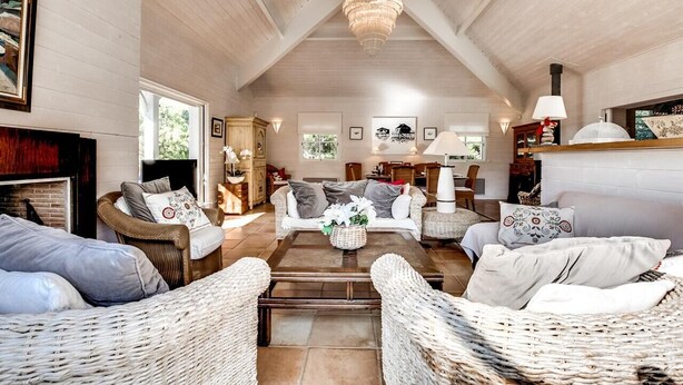 A spacious living room with high ceilings, wicker furniture, a fireplace, and a chandelier. - Charming villa with heated swimming pool between pool and ocean at Cap Ferret (Lège-Cap-Ferret)