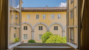 A view from a window of a building with a yellow facade, multiple windows, and a tiled roof. - Comfortable Convenient Apartment with Garden Views (Lucca)