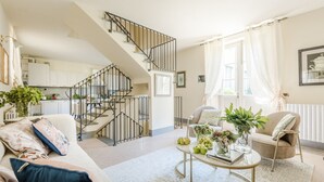 A spacious living room with a staircase, a dining area, and a kitchen in the background. - Comfortable Convenient Apartment with Garden Views (Lucca)