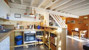 Cozinha compacta com armários de madeira, forno embutido e micro-ondas.