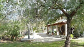 A house with a covered patio, surrounded by a garden with various plants and a swing set. - House / Villa - Selva (Caimari)