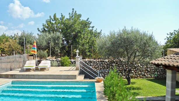 A swimming pool with lounge chairs and a stone wall in the background. - House / Villa - Selva (Caimari)