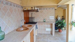 A kitchen with two sinks, a hanging rack, and a tiled backsplash. - House / Villa - Selva (Caimari)