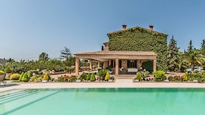 A pool with a covered seating area, a building with a green roof, and various landscaped gardens.