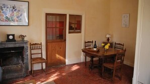 A dining area with a wooden table and chairs, a fireplace, and a door with glass panels. - COMFORT air-conditioned house with garden, terrace in Medieval City in Burgundy (Semur-En-Auxois)