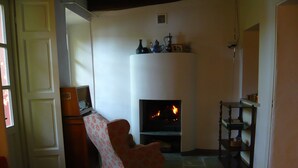 Una sala de estar con chimenea, televisor y un sofá rojo.