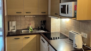 Una cocina compacta con armarios de madera, microondas, tostadora y lavavajillas.