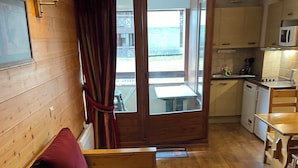Un espacio habitable pequeño con un sofá de madera, una mesa de comedor y una zona de cocina.
