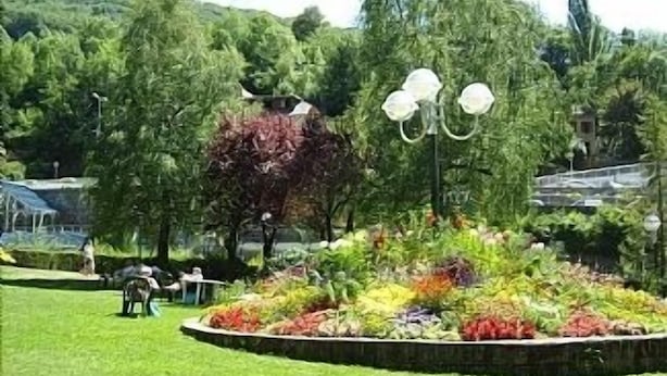 Un jardín con un parterre circular, un banco y un farol.